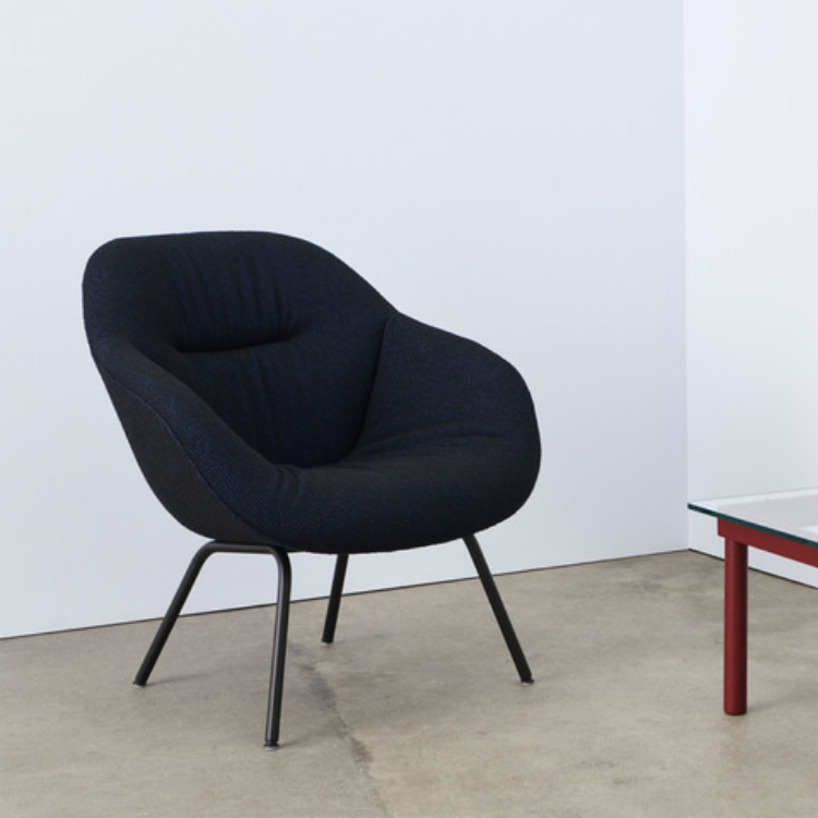 AAL 87 Soft lounge chair with dark blue quilted upholstery and slim black metal legs in a minimal room.