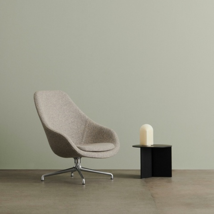 AAL 91 high-back lounge chair in grey upholstery on a swivel base, placed next to a small side table.