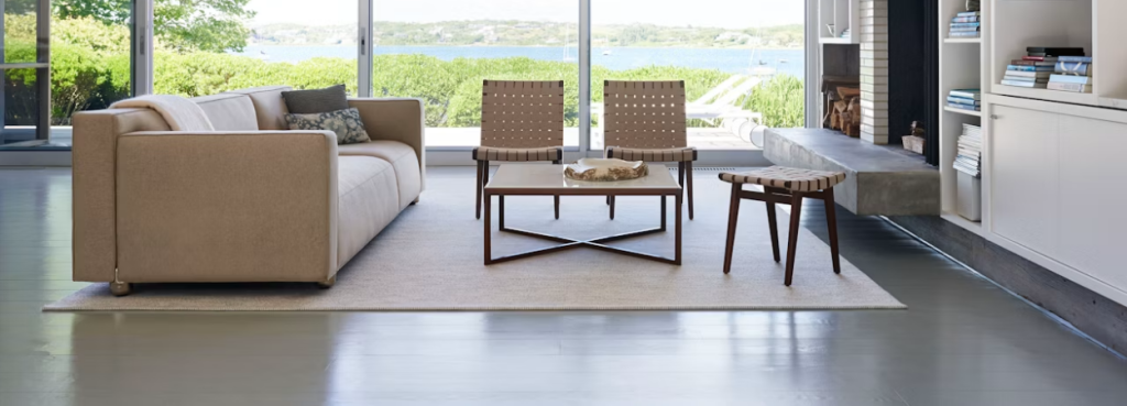 Risom Stool with dark tapered legs and woven cotton seat placed in a spacious, light-filled contemporary living room.
