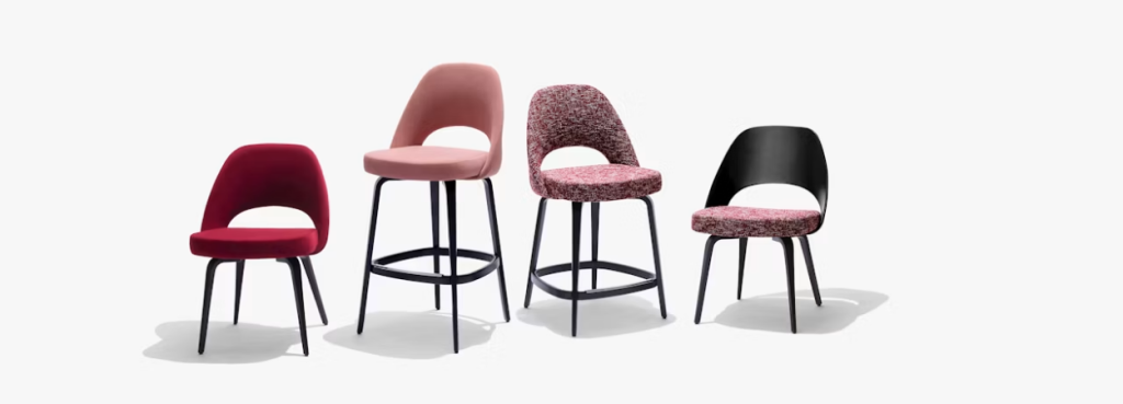 Four Saarinen Executive Stools with varying heights and diverse pink, red, and patterned textile upholstery.