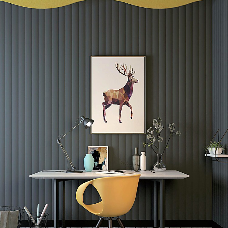 Valen Wave 70mm Acoustic Panel in dark grey with soft vertical ripples behind a desk, artwork, and a yellow chair.