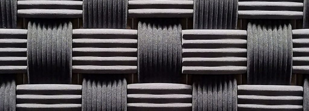 Close-up of Weave 3D acoustic panel in dark grey ribbed PET felt with an over-and-under basket weave design.